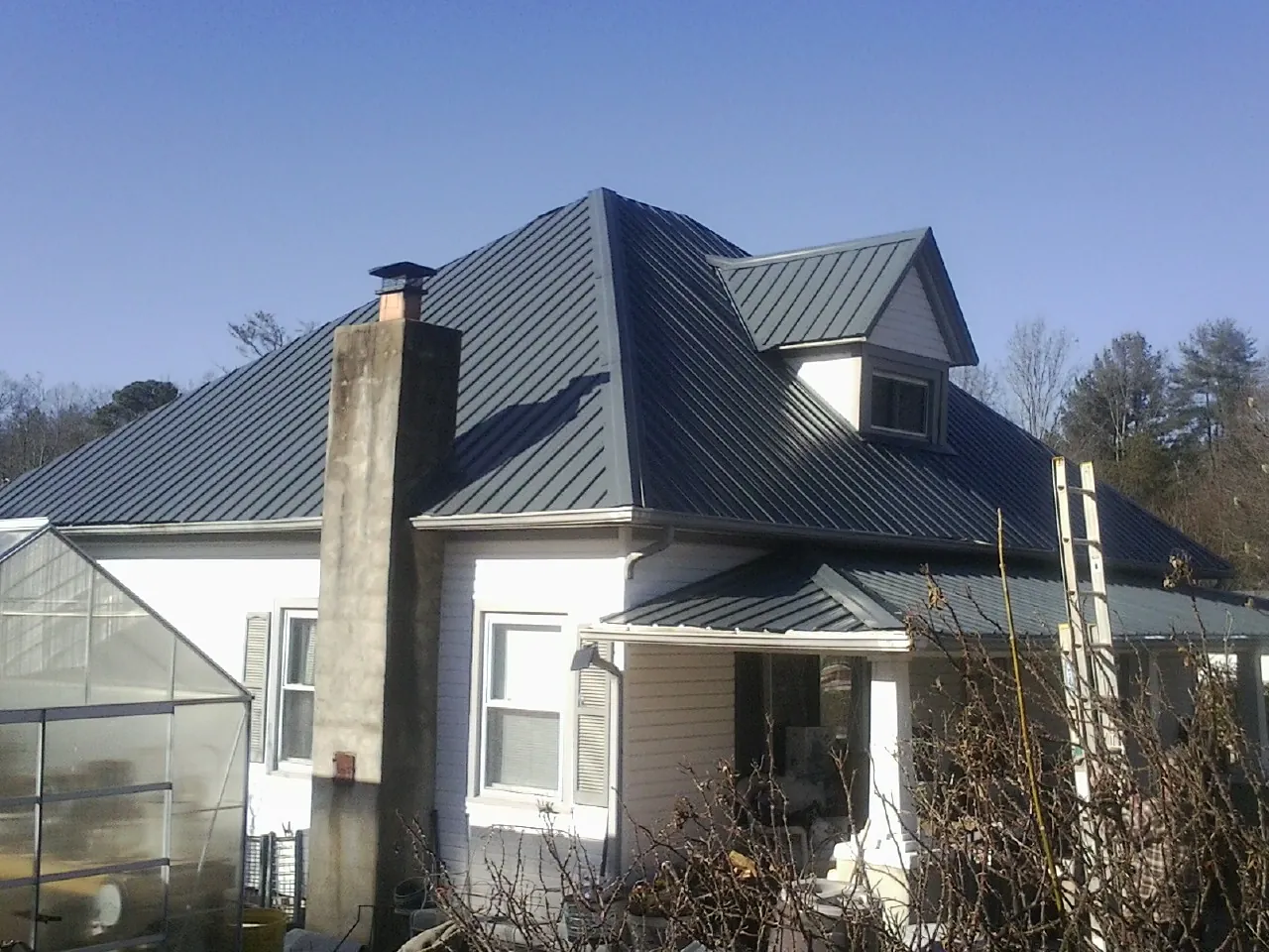 Dark blue standing seam metal roof on a white farmhouse with dormer — Slate & Tile Roof Repair by Roofing Brothers in Arcola