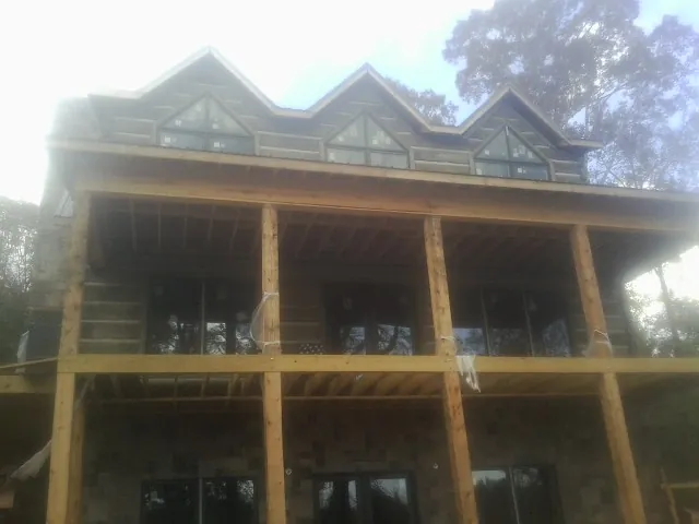 Dormers and porch framing on a large log home under construction — Roof Coating work by our crew in Arcola