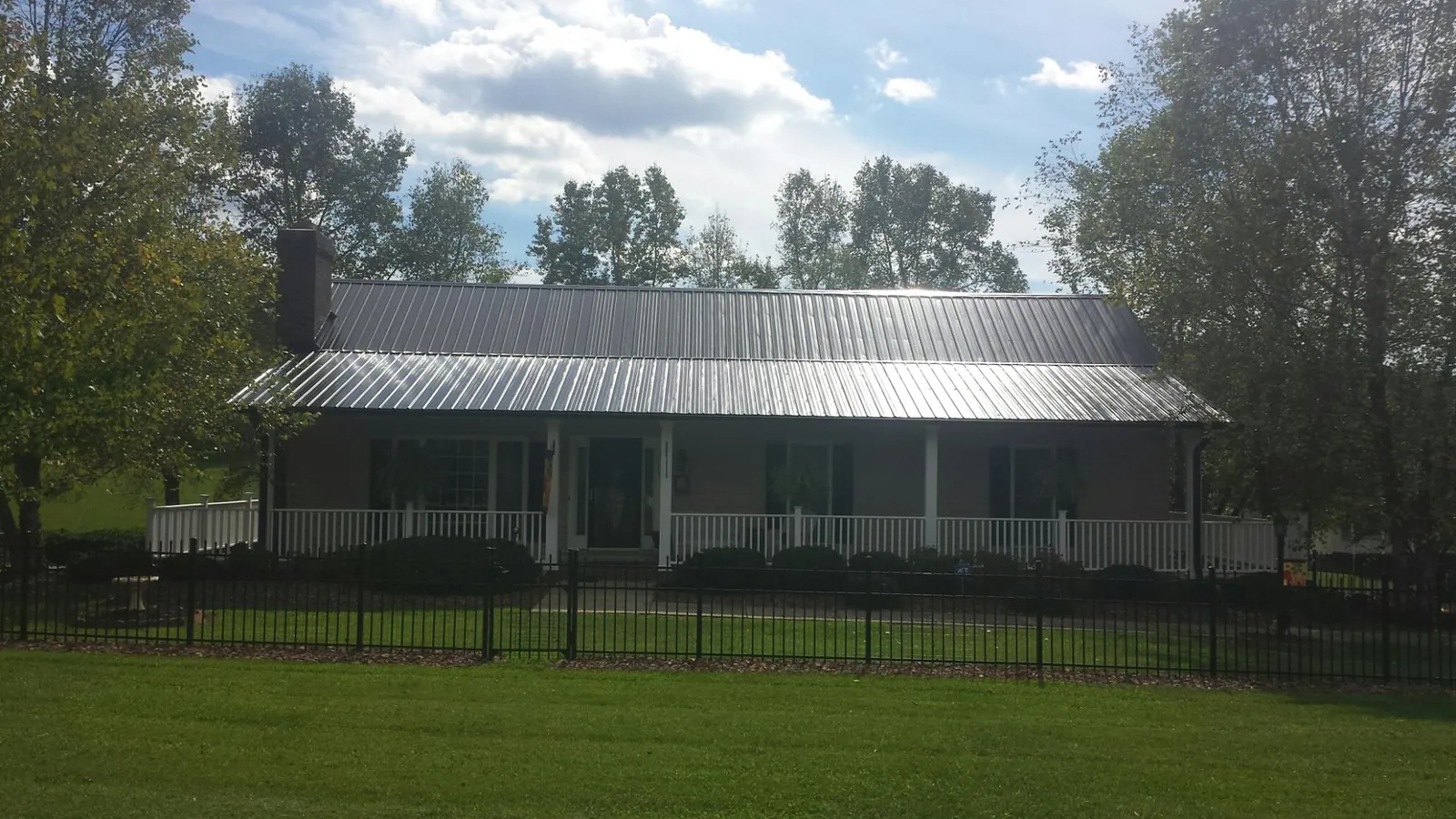 Gray metal roof on a brick ranch with a full width front porch — Gutter Guard Installation work by our crew in Arcola