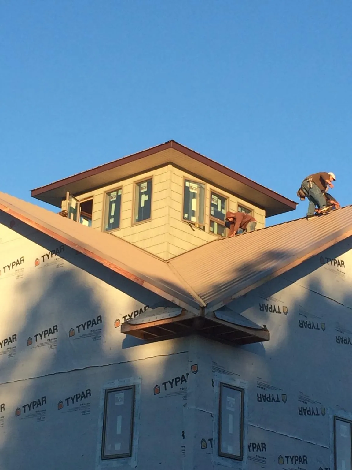 Roofers working around a rooftop cupola on a new metal roof at sunset — Roof Waterproofing in Arcola by Roofing Brothers